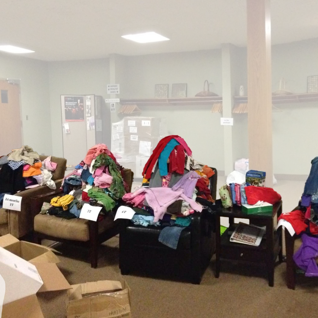 Armchairs and tables stacked with sorted donated children's clothing